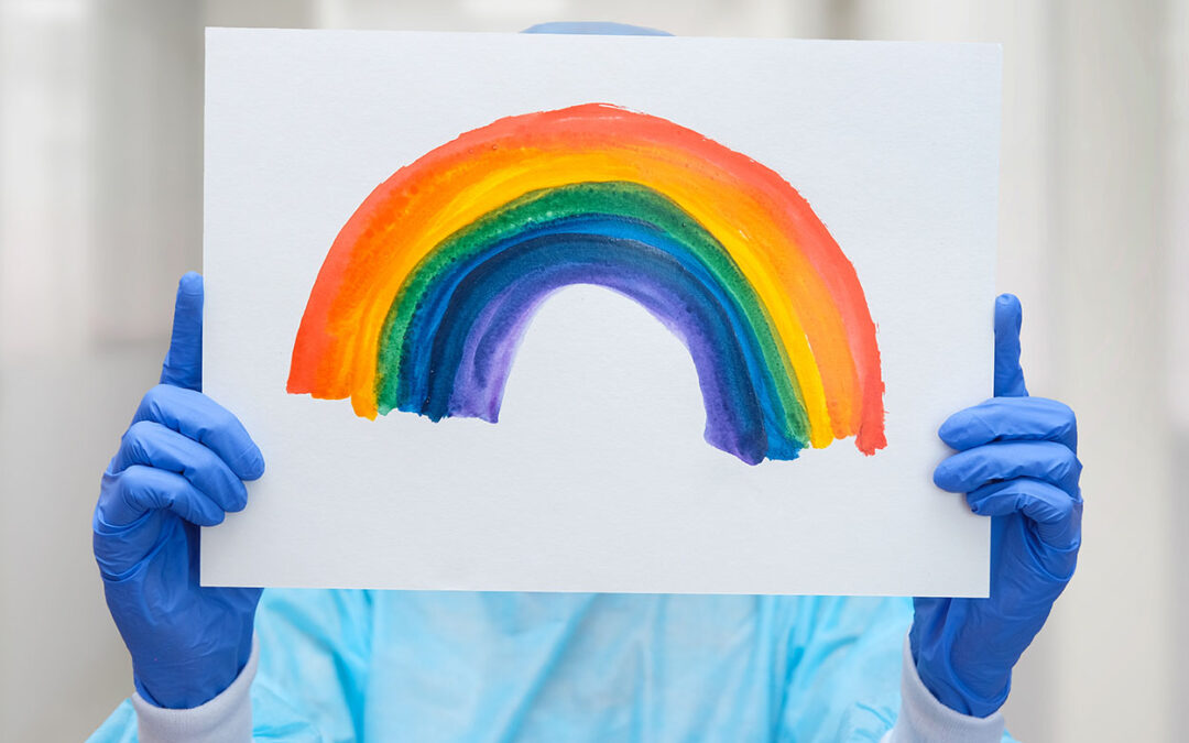 Infermiere con in mano un disegno di un arcobaleno